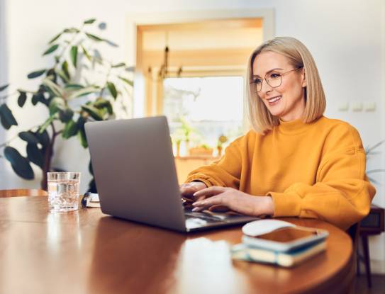 Frau in gelbem Pullover mit Laptop
